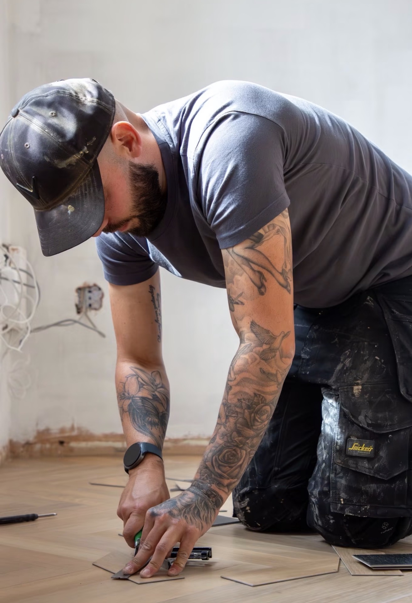 Sam carefully fitting flooring around the edge of a room