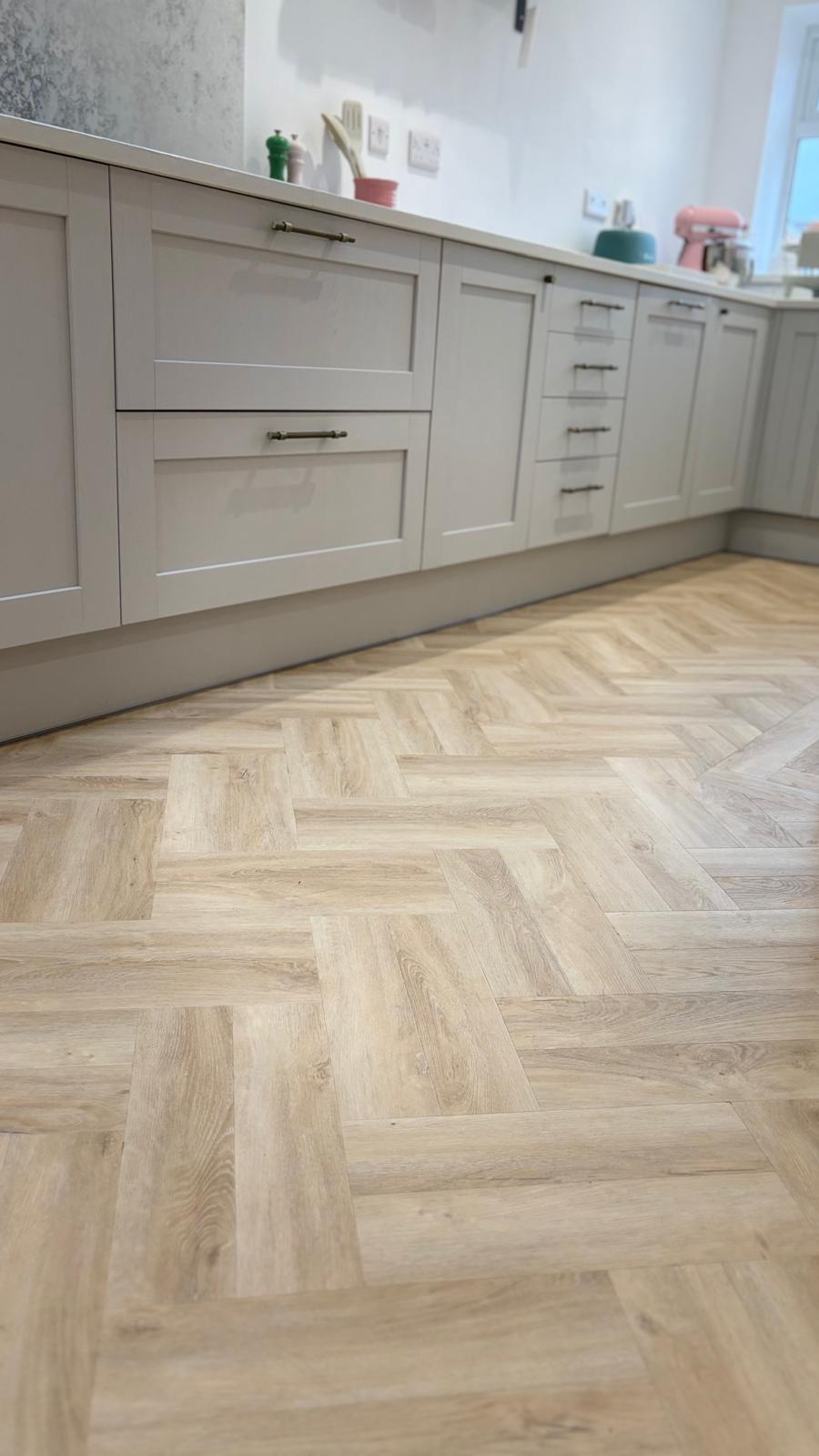 Low viewpoint showing herringbone LVT beneath kitchen units